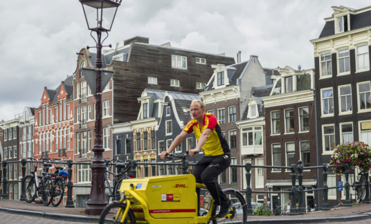 StadsdistributieStadsdistributie – Parcel Delivery Man On Bike In Amsterdam –  DHL – Fietskoerier – Cargobike – binnenstad