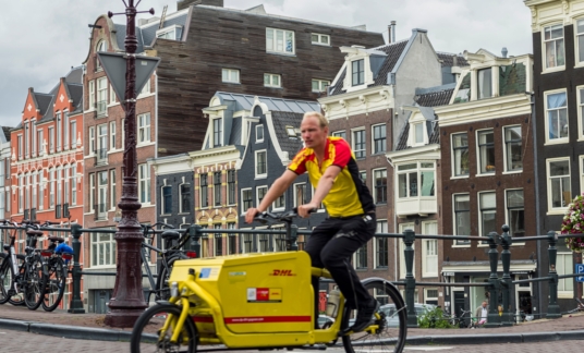 Parcel Delivery Man On Bike In Amsterdam –  DHL – Fietskoerier – Cargobike – binnenstad