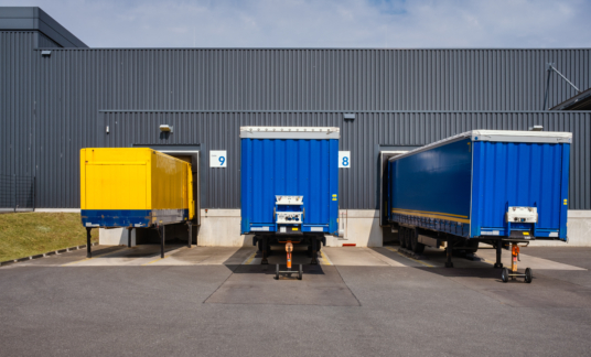 trucks and trailers at loading ramps of a warehouse