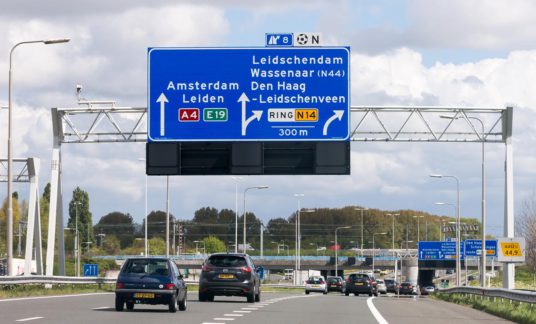 Motorway A4 with traffic and route signs, The Hague, Netherlands