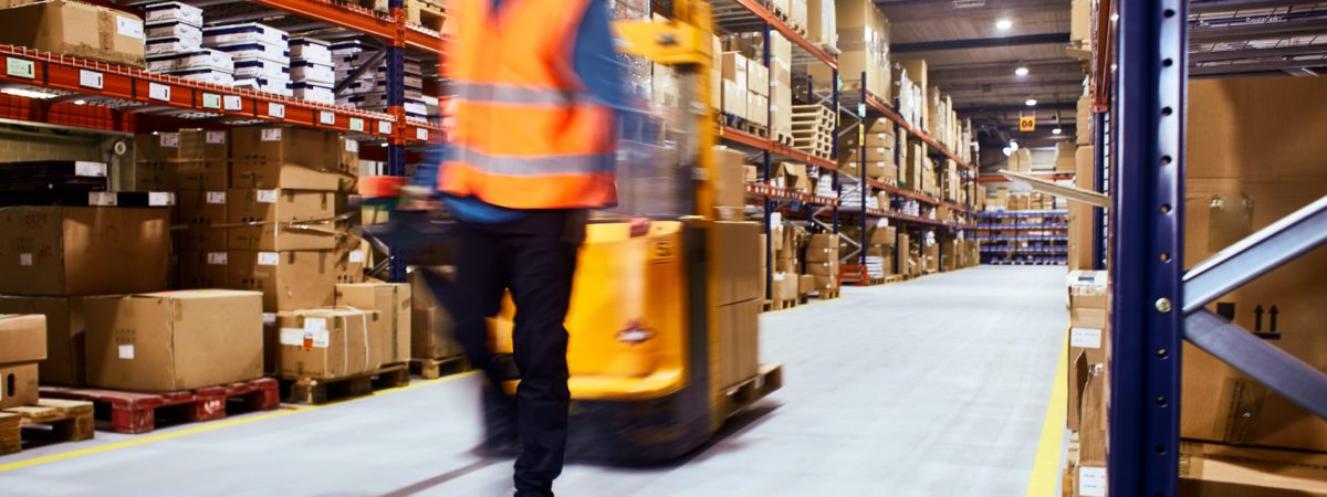 Warehouse, worker with a forklift in motion blur.