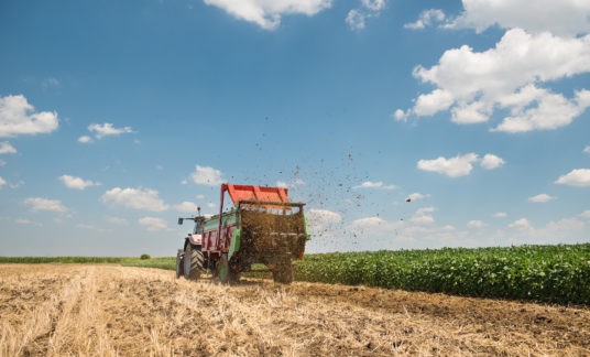 A tractor spreading manure on a field